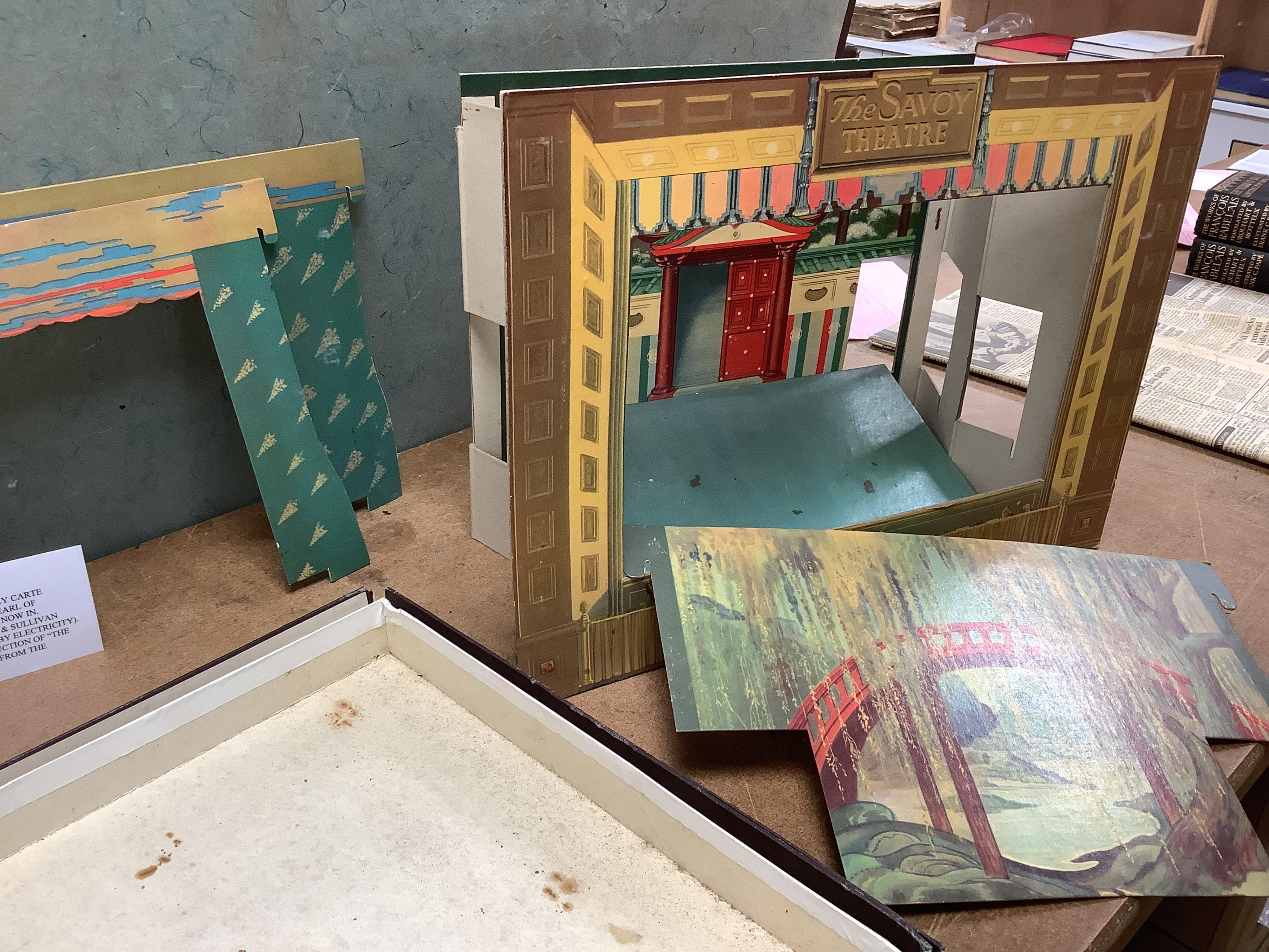 A Gilbert and Sullivan Opera model theatre, with printed card figures from the Mikado, together with a portrait photograph of Sir Arthur Sullivan loosely contained within a stained wood frame, the photograph is unmounted